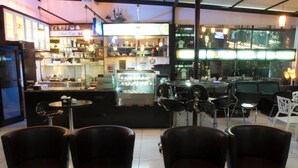 A cafe with a counter, chairs, and a display case. - House of Arsonia Bougainvillea (Jakarta)
