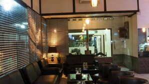 A modern lounge area with black leather sofas and chairs, a glass coffee table, and pendant lighting. - House of Arsonia Bougainvillea (Jakarta)