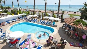 A poolside area with lounge chairs and umbrellas, a hot tub, and a view of the beach and ocean. - Parador Beach Hotel (Alanya)