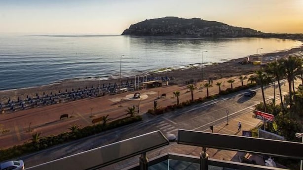 A coastal road with a beach and a hill in the background. - Parador Beach Hotel (Alanya)