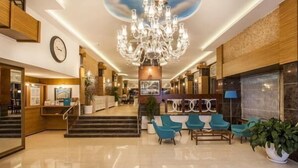 A hotel lobby with a chandelier, seating area, and a staircase leading to the upper floors. - Parador Beach Hotel (Alanya)