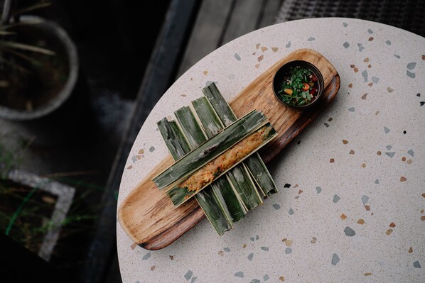 A round table with a wooden serving board and a bowl of sauce.