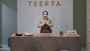A reception desk with a logo, a person standing behind it, and a display of food items. - The Hills Batam (Batam)