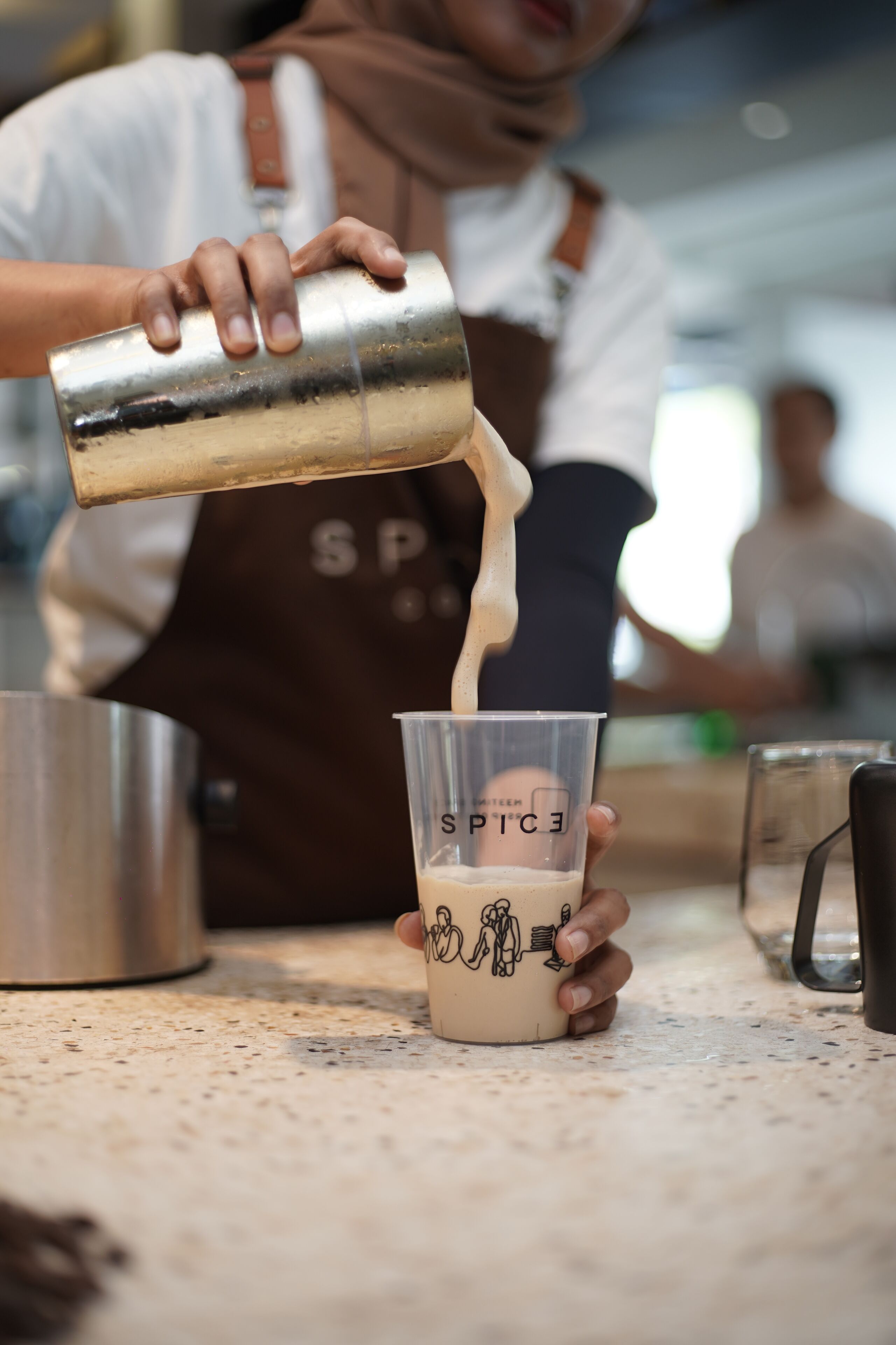 Una persona sirviendo una bebida en una taza con un diseño.