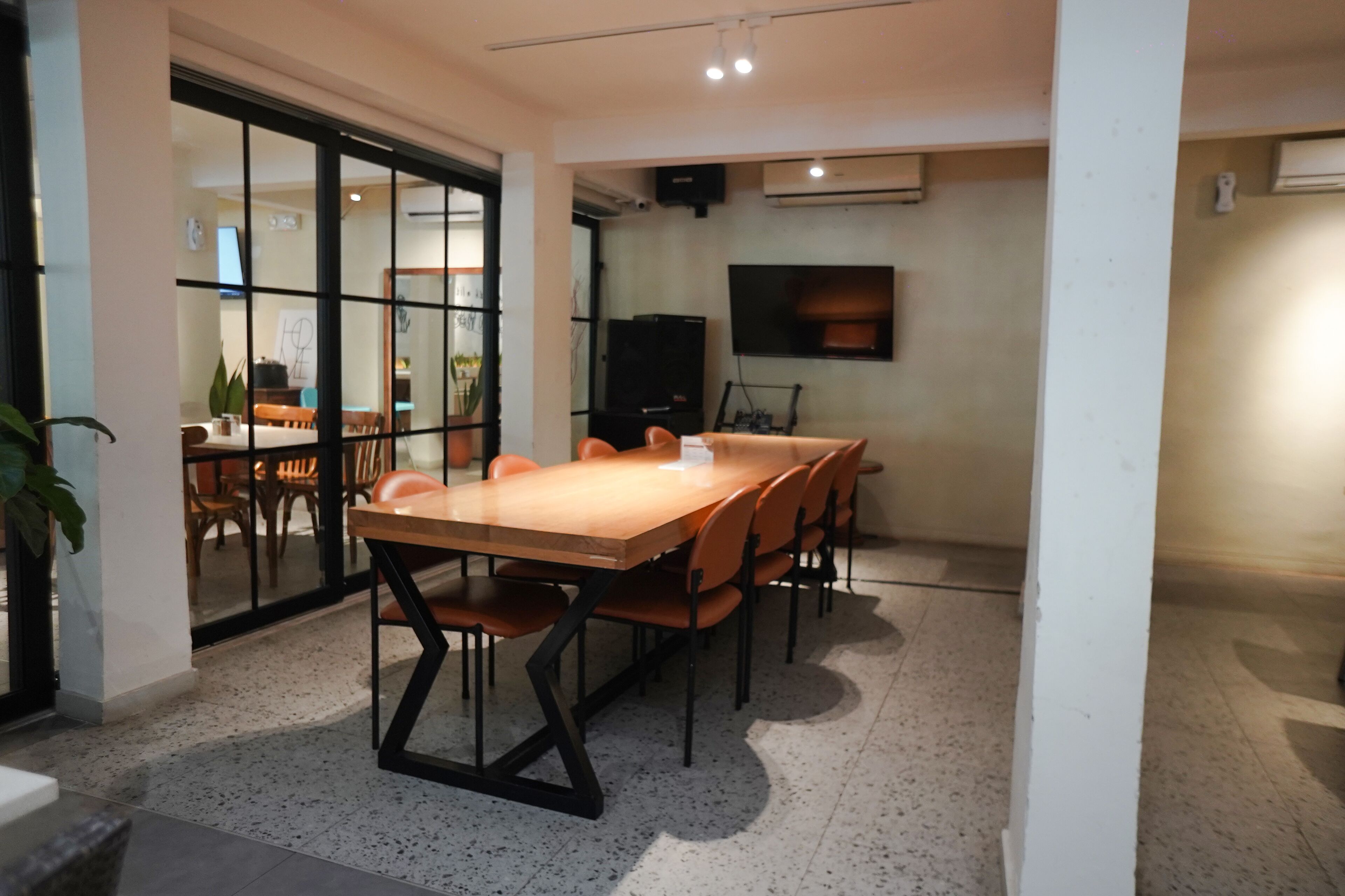 A conference room with a long table, chairs, and a television on the wall.