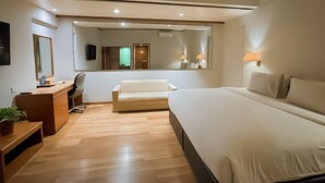 A hotel room with a bed, a desk, a chair, a sofa, a TV, a mirror, and a bathroom visible through an open door. - The Hills Batam (Batam)