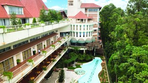 A hotel with a central swimming pool, multiple balconies, and a tower with a red roof. - Golf Course Hotel (Kampala)