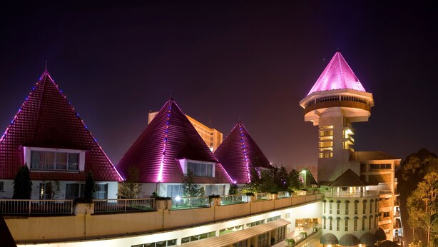 A hotel with multiple floors, outdoor swimming pool, and a tower with a conical roof. - Golf Course Hotel (Kampala)