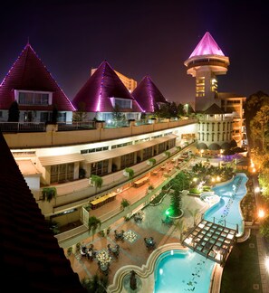 A hotel with multiple floors, outdoor swimming pool, and a tower with a conical roof.