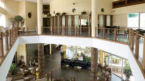 A spacious lobby with a central seating area, multiple levels, and a view of the outdoor area. - Golf Course Hotel (Kampala)