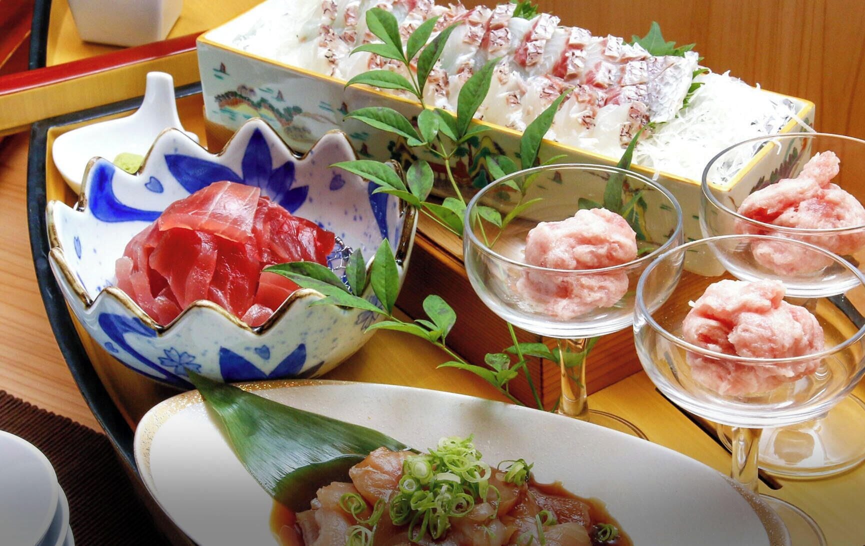 A variety of Japanese dishes including sashimi, sushi, and a bowl of rice with green onions.