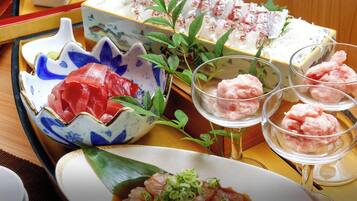 Forskellige japanske retter, heriblandt sashimi, sushi og en skål ris med forårsløg.