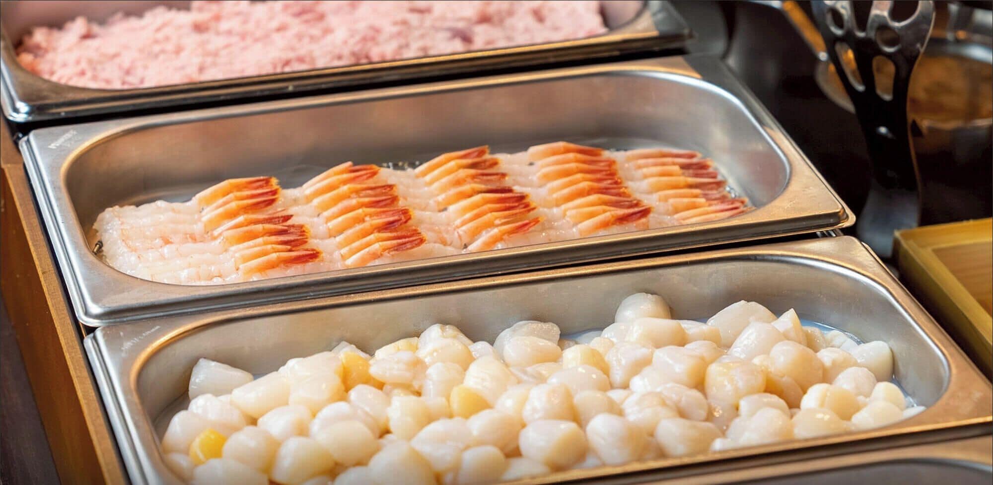 Un buffet proposant un choix de fruits de mer, notamment des crevettes et des noix de Saint-Jacques.
