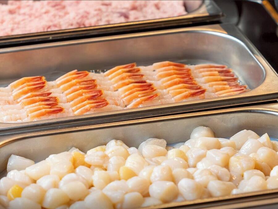 Un bufé con opciones de mariscos, incluyendo camarones y vieiras.