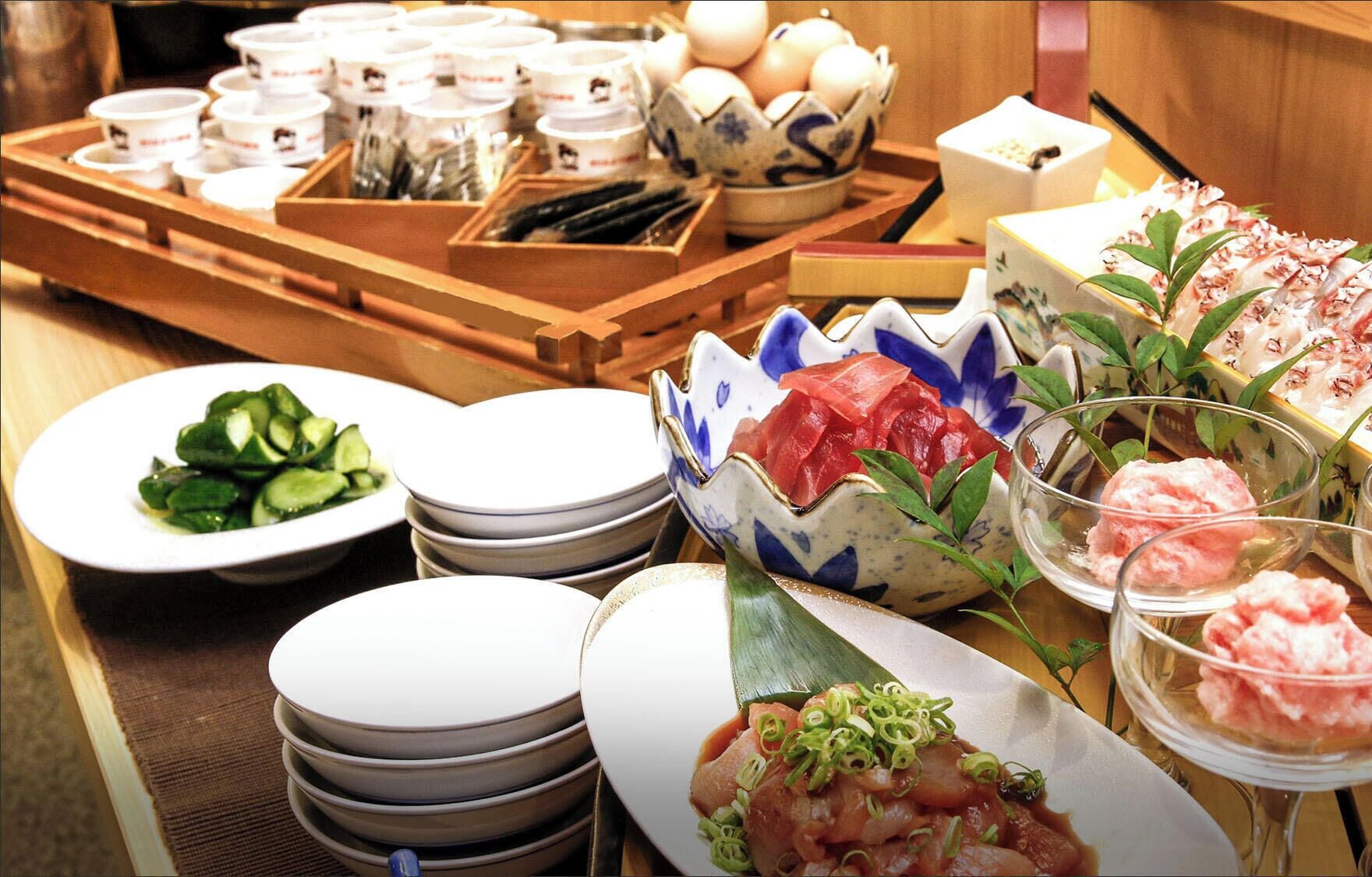 A variety of dishes and utensils on a table, including plates, bowls, and a tray with cups and chopsticks.
