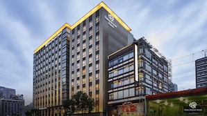 A modern high-rise hotel with a prominent logo at the top, multiple floors, and a corner entrance. - Daiwa Roynet Hotel Matsuyama (Matsuyama)
