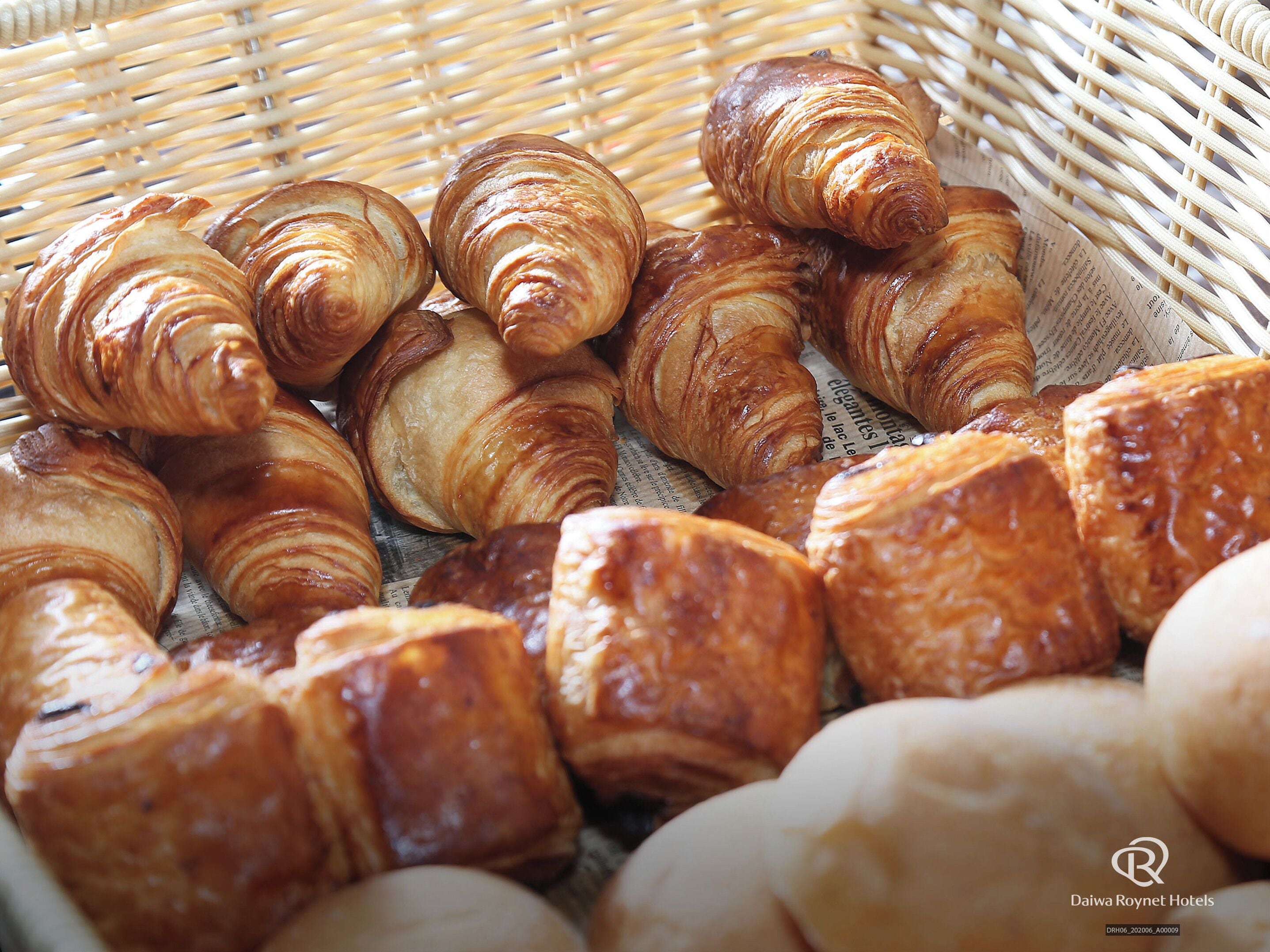 Ein Korb mit verschiedenen Backwaren, darunter Croissants und Brötchen.