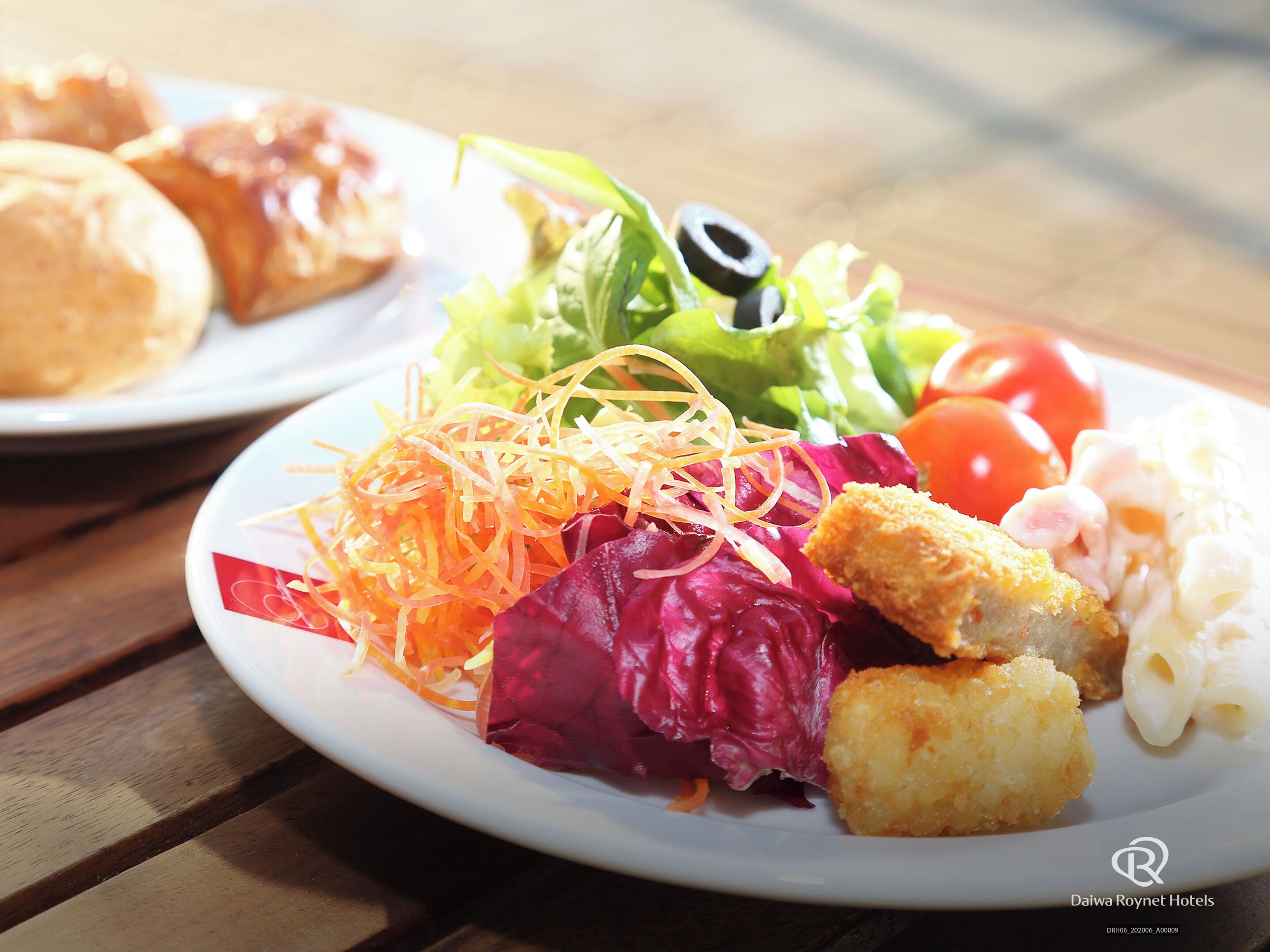 Plat amb una amanida, incloent pastanagues ratllades, lletuga i tomàquets, juntament amb altres aliments.