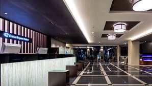 A modern hotel lobby with a reception desk, seating area, and a check-in counter. - Daiwa Roynet Hotel Matsuyama (Matsuyama)