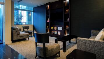 Un moderno vestíbulo de hotel con una pared azul oscuro de acento, una amplia estantería y asientos cómodos.