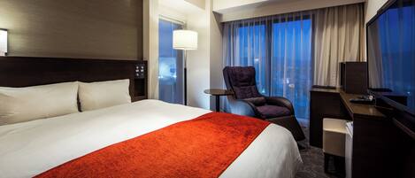 Une chambre d’hôtel avec un grand lit, un bureau, une chaise et un téléviseur.