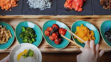 A variety of dishes on a wooden table, including rice, vegetables, and meat.