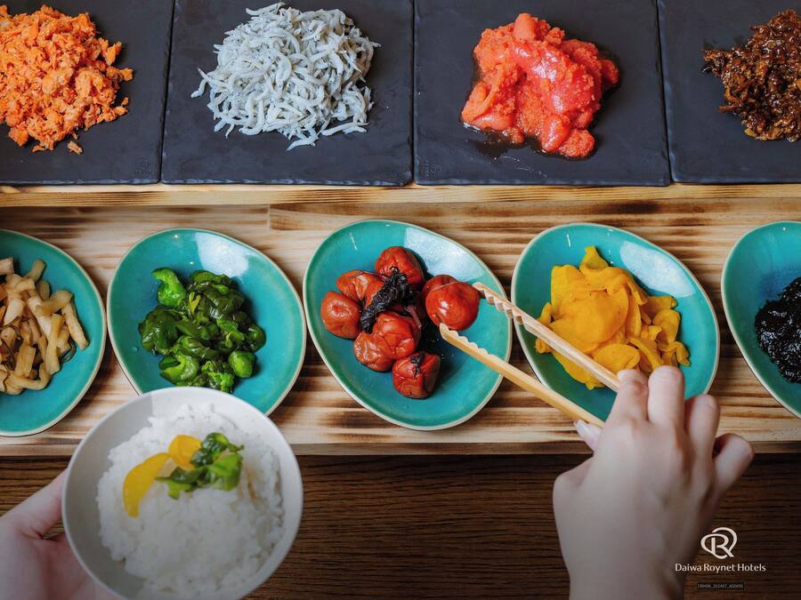 A variety of dishes on a wooden table, including rice, vegetables, and meat.