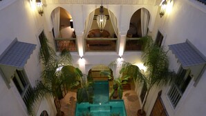 A courtyard with a swimming pool, potted plants, and a seating area with a sofa and cushions. - Riad Palacio de las Especias (Marrakech)