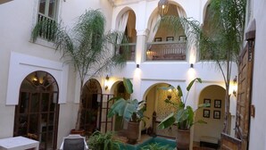 A spacious courtyard with multiple seating areas, potted plants, and a pool. - Riad Palacio de las Especias (Marrakech)