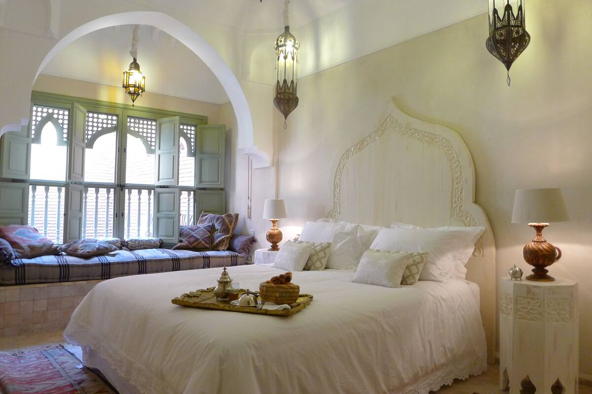 A spacious bedroom with a large bed, a seating area with a view, and decorative lighting.