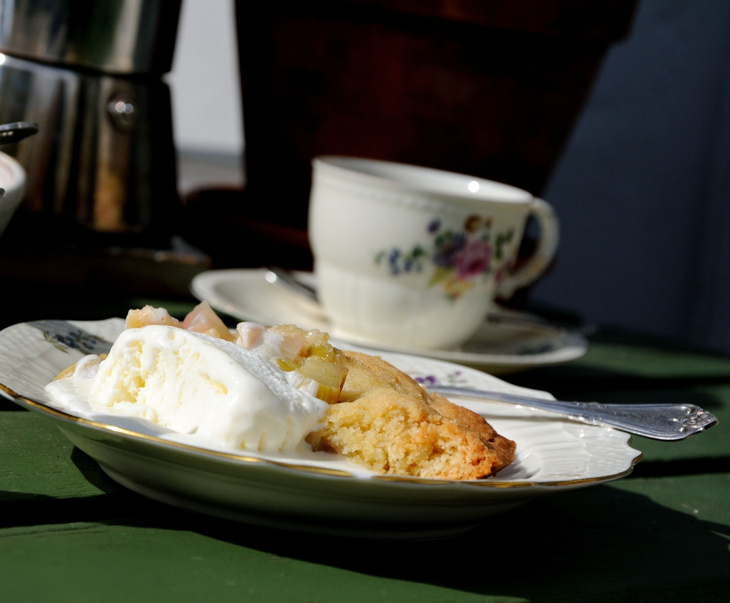 A plate with a piece of cake and a scoop of ice cream on a green table.
