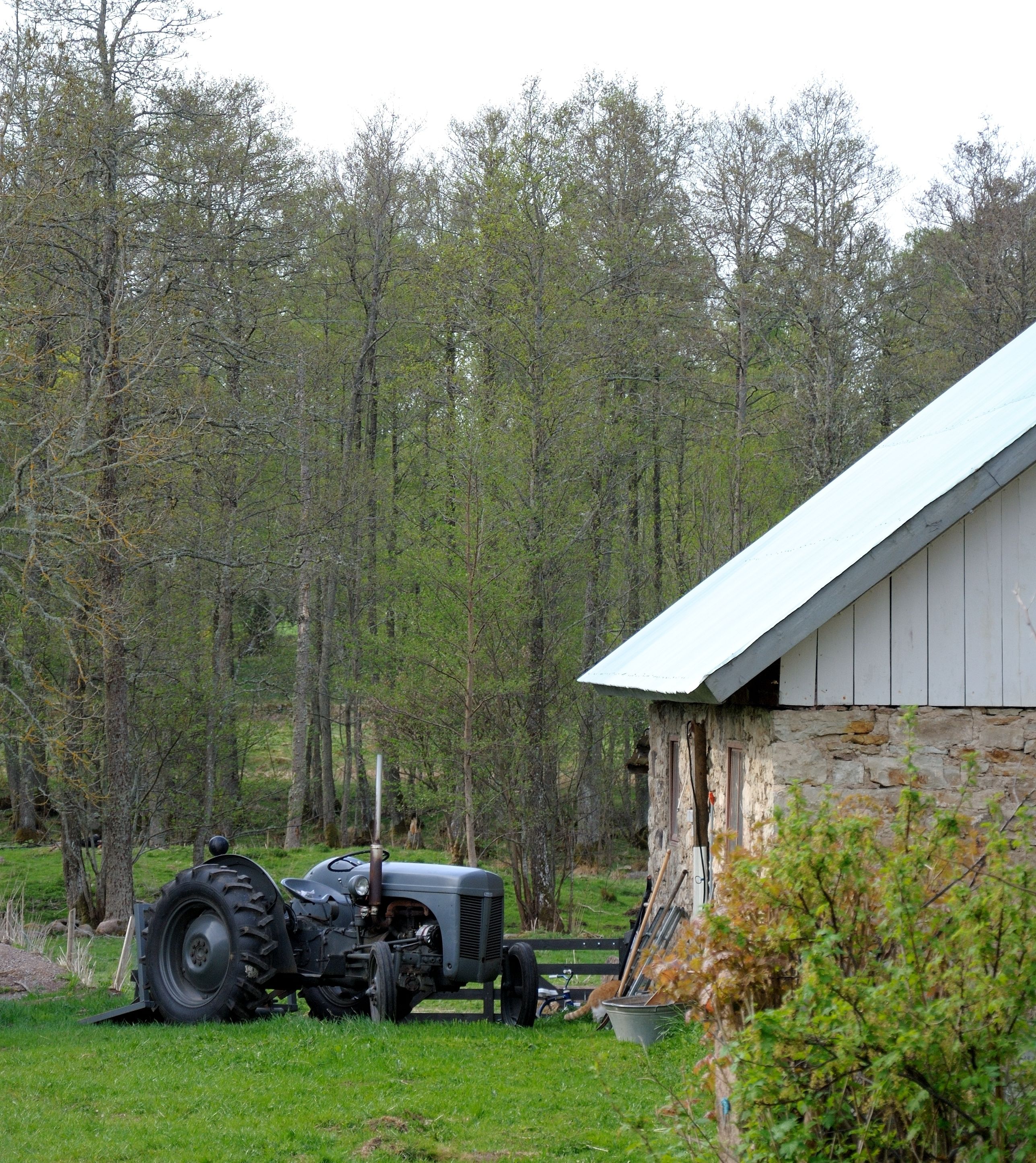 Une grange située en zone rurale, avec une façade en pierre et un toit en métal.