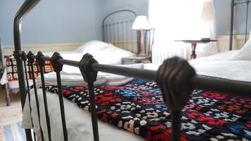 A bed with a colorful blanket, a metal headboard, and a bedside table with a lamp.