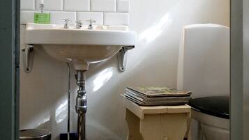 A bathroom with a white sink, mirror, and a small wooden stool.