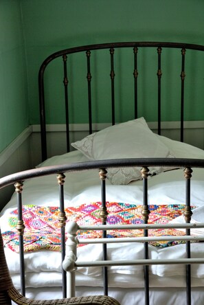 Un lit avec un cadre en métal et une couette aux couleurs vives.