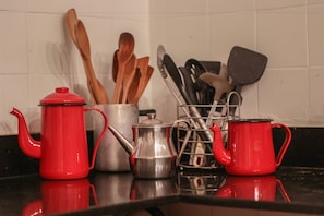 A kitchen counter with a red teapot, a silver pot, and a metal utensil holder. - Hospedaria Rio - Hostel (Rio de Janeiro)