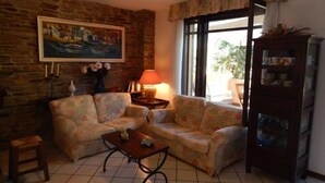 A cozy living room with a sofa set, a coffee table, a lamp, a painting on the wall, and a cabinet with glass doors.