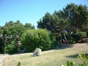 A stone sculpture in a grassy area with trees and a building in the background. - AbitaSardegna Stintino (Stintino)