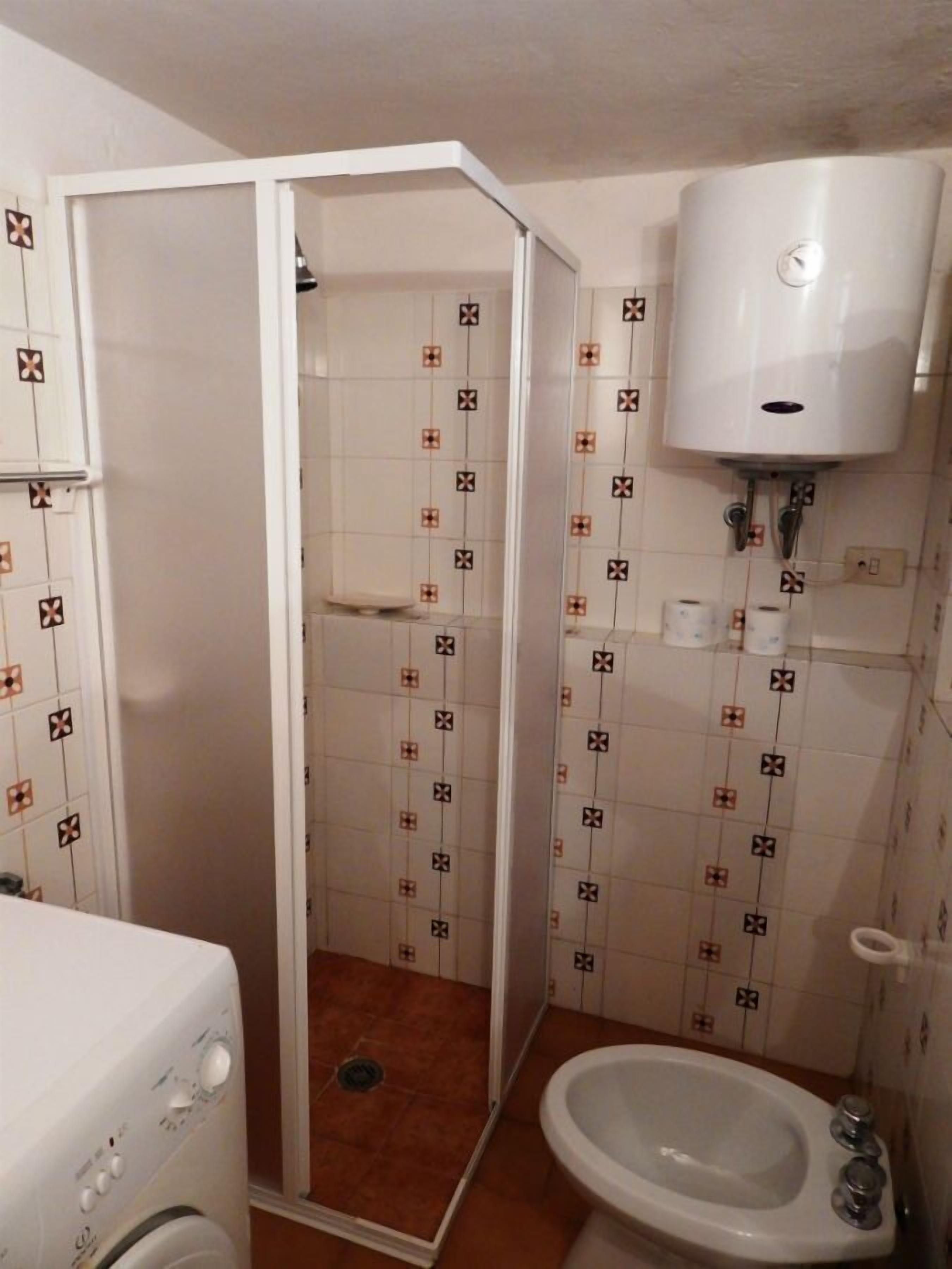 Ein Badezimmer mit Dusche, Toilette und Waschmaschine.