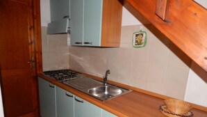 A compact kitchen with a gas stove, sink, and light blue cabinets. - AbitaSardegna San Teodoro (San Teodoro)