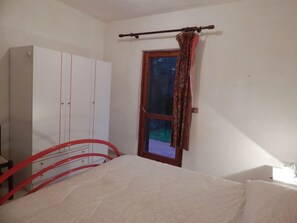 A bedroom with a bed, a wardrobe, a window with curtains, and a red metal bed frame.