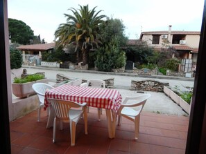 A patio with a table and chairs, a palm tree, and a stone wall.
