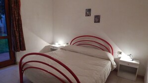 A bedroom with a bed, two bedside tables, and a window with curtains. - AbitaSardegna San Teodoro (San Teodoro)