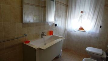 A bathroom with a white sink, a mirror, a toilet, and a bathtub.