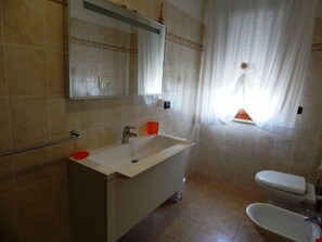 Un baño con un lavamanos blanco, un espejo, un inodoro y una bañera.