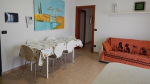 Un comedor con una mesa y sillas, un cuadro en la pared, un sofá y un reloj también en la pared.