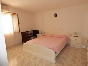 Una camera da letto con un letto, un comodino, una cassettiera e una finestra con tende.