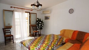 Una habitación con cama, sofá, sillón, mesa, planta en maceta y candelabro.