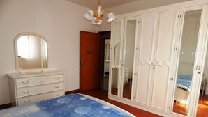 Un dormitorio con cama, cómoda, armario y espejo.