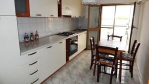 Una cocina con armarios blancos, una estufa a gas y una mesa de comedor con sillas.